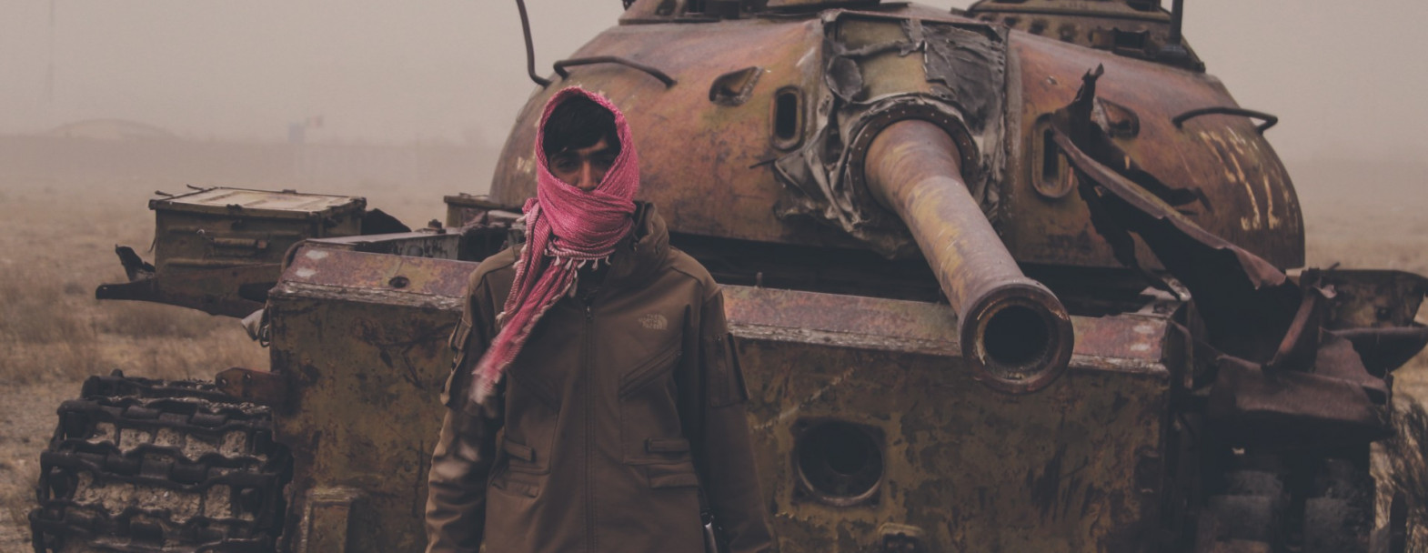 Août 2021, dans un faubourg de Kaboul (Afghanistan), un homme armé pose devant une épave de tank taliban. / ©iStock/Trent Inness