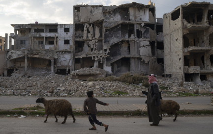 Un enfant court après les moutons en passant devant des bâtiments détruits pendant la guerre civile dans le quartier de Khalidiya à Homs, en Syrie, mercredi 1er janvier 2025. / Keystone